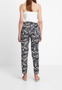 Námořnické kalhoty s bílým vzorem listů, vysoký pas, elastický pas a zúžené nohavice. Nenošené s bílou topem a sandály.