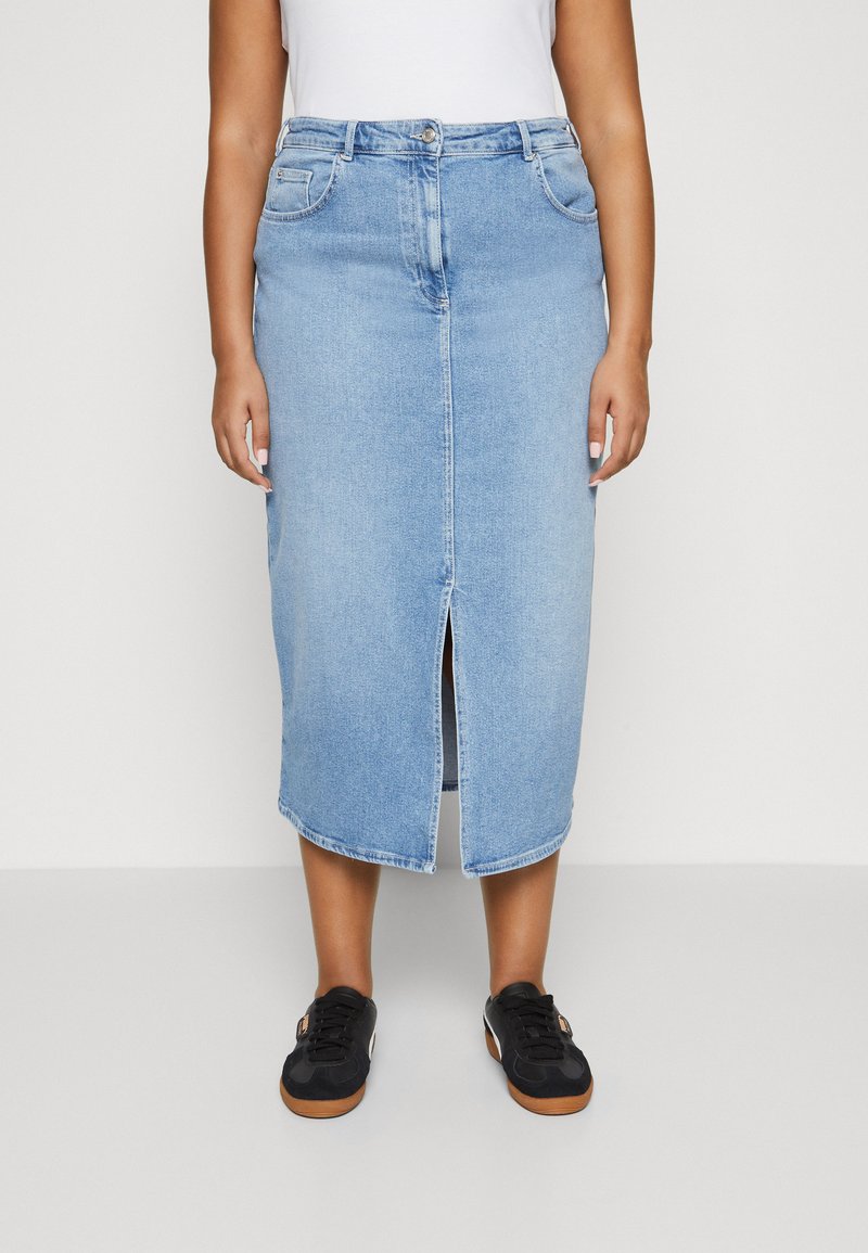 Lys blå denimskjørt med en frontsplitt, som har knappeåpning, beltehemper og to frontlommer, kombinert med svarte joggesko.