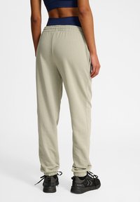 Ljust gröna joggers med elastisk midja och muddar vid anklarna, tillverkade av mjukt material. Kombineras med svarta, strukturerade träningsskor.