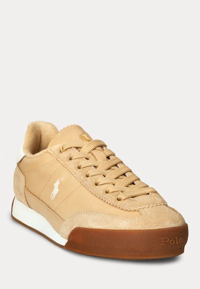 Sneaker color tan con pannelli in suede e tela, design con lacci, accenti bianchi e suola in gomma. Presenta un piccolo logo sul lato.