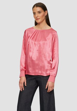 Roze satijnen blouse met driekwart mouwen, geplooide voorkant en elastische manchetten, gecombineerd met donker wijde broek.