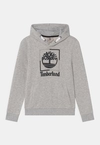 Szara bluza z kapturem wykonana z miękkiego materiału, z czarnym logo drzewa w kwadracie oraz napisem „Timberland”. Posiada kieszeń kangurka.
