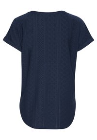T-shirt bleu marine à manches courtes présentant un motif complexe avec des perforations et un ourlet arrondi, fabriqué à partir d'un tissu texturé.