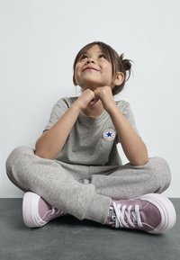 Siva pamučna majica s logom, odgovarajuće sive trenirke i ružičaste Converse tenisice s bijelim vezicama i debljim gumenim đonovima.