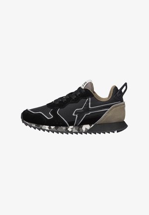 Baskets noires et beiges avec une semelle camouflage, à lacets à l'avant, en tissu texturé, et un logo stylisé en "X" sur le côté.