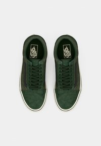 Green suede sneakers with white rubber soles, featuring a lace-up design, contrasting black stripe, and branded insole. Flat texture.