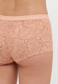 Sárgabarack színű női boxer alsónemű hullámos vonalmintával. Puha anyag, varrat nélküli kialakítással és márkás rugalmas derékpánttal.