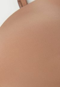 Lichtbruin stof met een gladde, geribbelde textuur, met een naadloos ontwerp en een verstelbare band op de achtergrond.