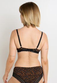 Reggiseno nero e slip a vita alta coordinati con motivo floreale arancione. Bordo in pizzo sui lati, spalline regolabili e chiusura a gancio sul retro.