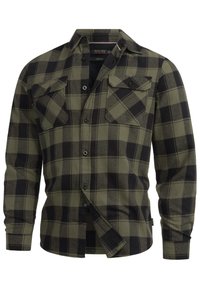 Camisa de franela a cuadros verdes y negros con cierre de botones al frente, dos bolsillos en el pecho y mangas largas. Textura suave, corte recto y diseño de cuello clásico.