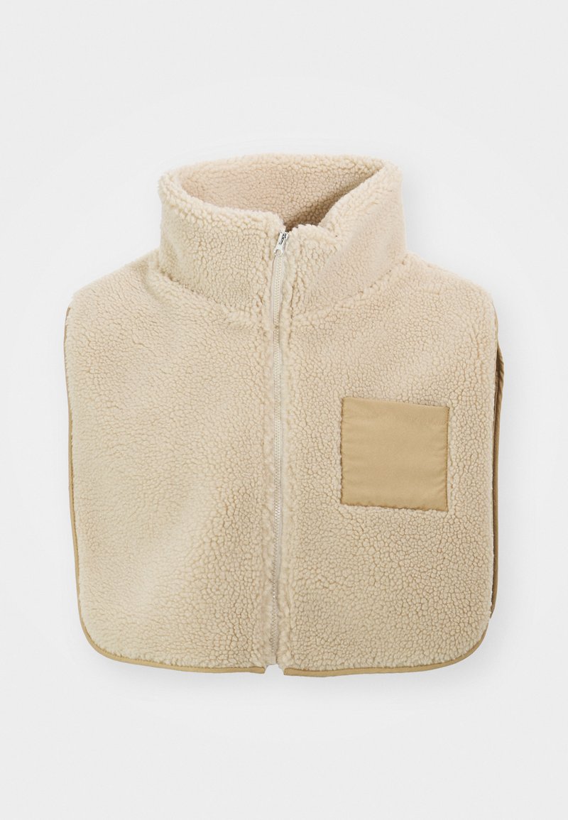 Gilet en polaire beige avec un col haut, une fermeture éclair à l'avant et une poche carrée. Il présente un tissu doux et texturé.