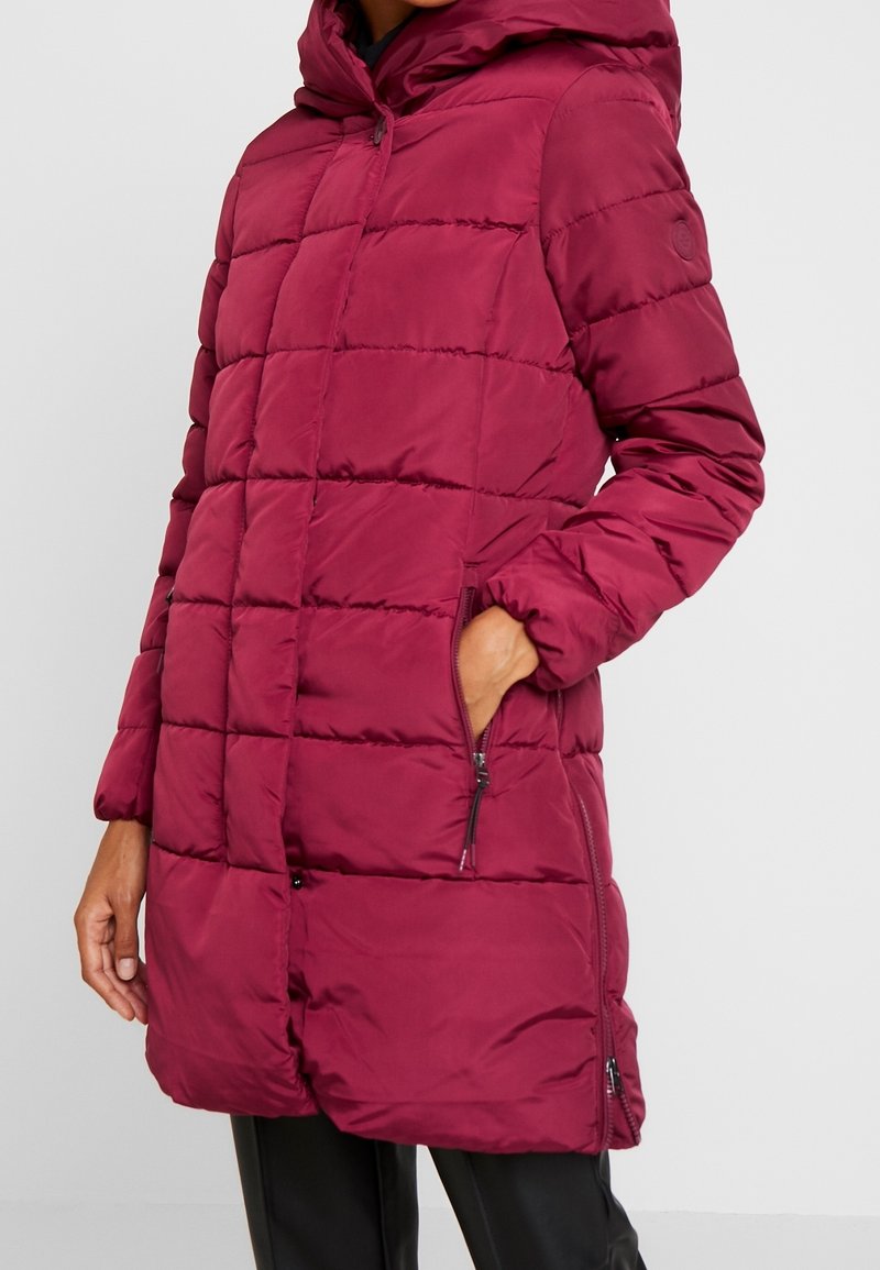 Bordeauxfarbene Daunenjacke mit Kapuze, mit einem gesteppten Design, Reißverschlusstaschen und langen Ärmeln. Hergestellt aus glattem, isoliertem Stoff.