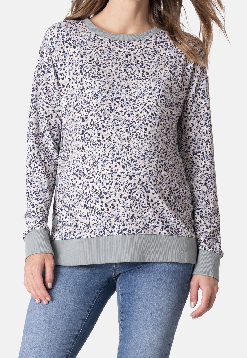 Un sweat à manches longues avec une base crème et un motif moucheté bleu marine et gris, un col et des poignets côtelés, et un ourlet côtelé.