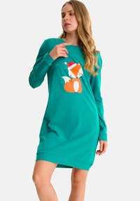 Turquoise langemouwen jurk met een oranje vosafbeelding die een rode kerstmanhoed draagt. Het materiaal lijkt zacht en glad met een relaxte pasvorm.