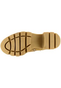 Suela de zapato con un diseño de goma beige que presenta un patrón de tacón texturizado para agarre y tres ranuras horizontales para flexibilidad.