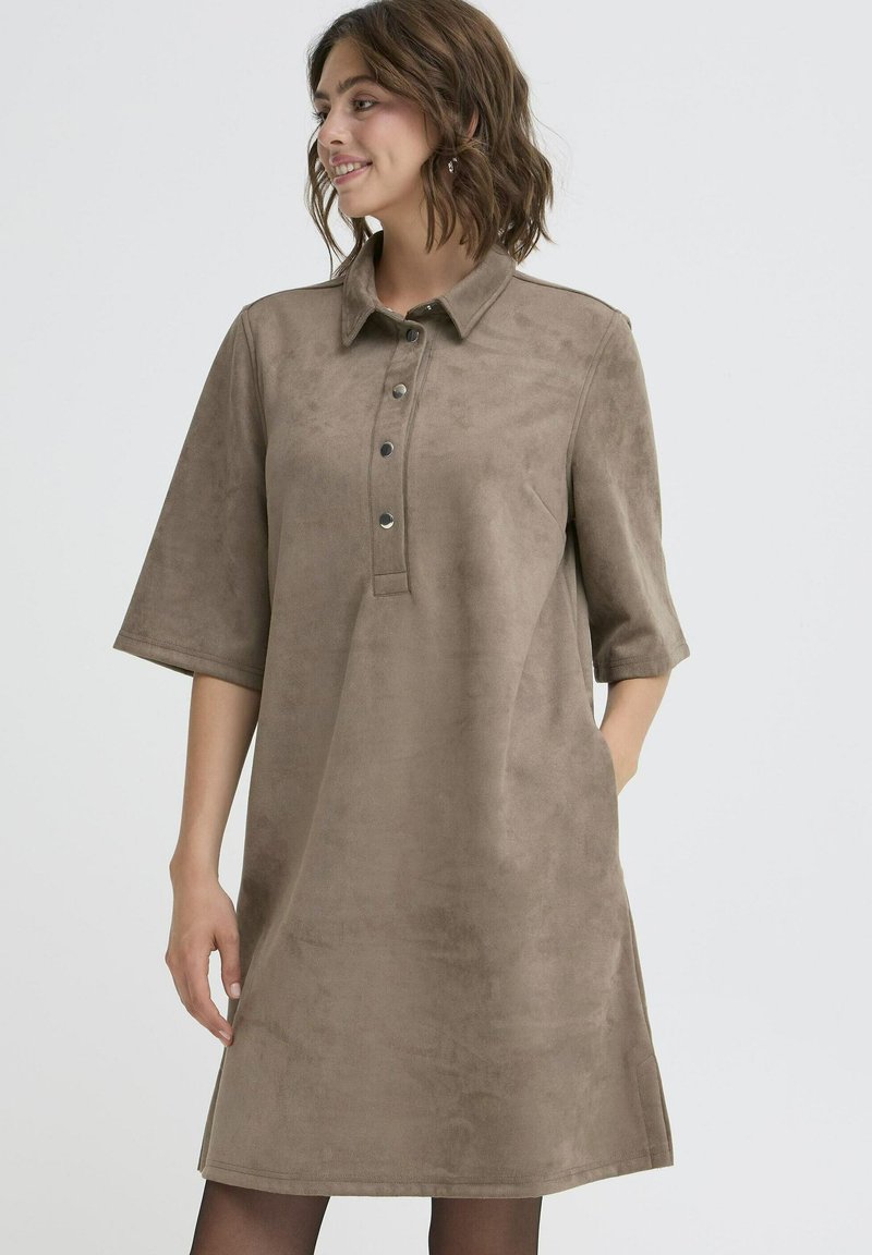 Rudos suede suknelė su apykakle, trumpomis rankovėmis ir penkiais mygtukais priekyje. Minkšta tekstūra ir laisvas, šiek tiek išskleistas siluetas.