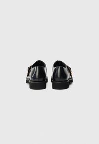 Navy leather shoes featuring a smooth finish, round toe, and contrasting black sole, with gold hardware accents on the side.