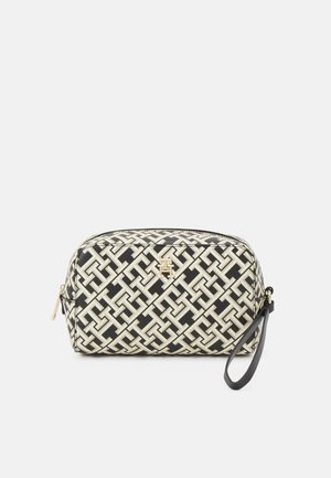 Borsa a pochette nera e crema con un motivo, forma arrotondata, hardware dorato, zip laterale e un bracciale nero.