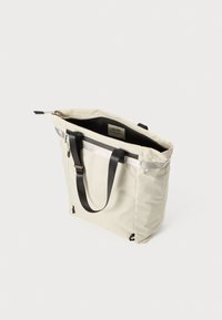 Sac fourre-tout beige avec des rayures verticales, poignées noires et accents argentés, doté d'une fermeture éclair et d'un label intérieur.