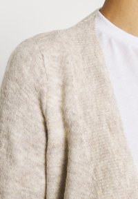 Beige cardigan made of soft knit material with a slightly textured finish; features open front and wide sleeves for a relaxed fit.