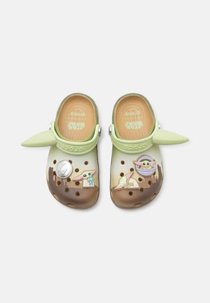 Crocs pour enfants sur le thème Star Wars avec des brides vertes en forme d'oreilles et des breloques du personnage Baby Yoda sur des chaussures marron et beige.