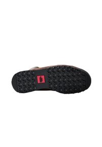 Zapato de cuero marrón con una suela de goma negra texturizada que presenta un patrón distintivo de estrellas. Acento rojo con el logo visible en la suela.