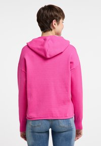 Felpa fucsia con cappuccio regolabile, polsini a costine e vestibilità comoda. Realizzata in un materiale morbido, presenta una texture liscia e un design semplice.