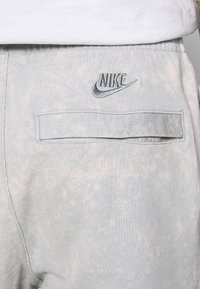 Ljusblå Nike sweatshirtbyxor med en texturerad yta. Har en bakficka och en broderad Nike-logga i grått på midjebandet.