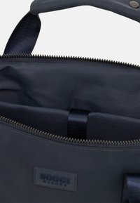 Borsa a mano blu navy con esterno liscio, chiusura con cerniera e tasca interna. Dotata di etichetta e manici in tessuto per un facile trasporto.