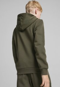 Sudadera verde con una textura suave, puños y dobladillo acanalados, y capucha con cordón. Presenta un diseño simple y funcional.