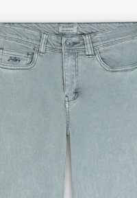 Jeans de mezclilla de color azul claro con cierre de botón, diseño de cinco bolsillos y costuras en contraste. Presenta el logo "Scalpers" en el bolsillo delantero.