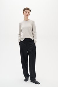 Light gray sweater with long sleeves, paired with high-waisted black trousers, smooth texture, and black slip-on shoes.