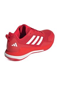 Baskets de sport rouges avec une tige en maille, semelle en caoutchouc et rayures blanches. Dotées d'un col rembourré et d'un talon texturé pour le soutien.