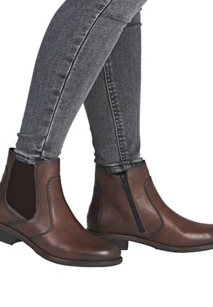 Braune Lederstiefeletten mit glatter Oberfläche, elastischen Seitenpanelen und einem Reißverschluss, kombiniert mit schmal geschnittenen grauen Jeans.