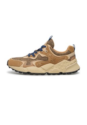 Vista laterale di una sneaker marrone e beige con texture, lacci blu scuro e suola spessa in gomma con motivi a triangolo.