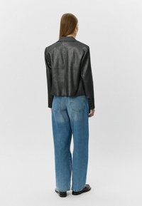 Kort zwart blazer met een metallic uitstraling, met notch revers en knoopaccenten, gecombineerd met hooggewaisted, loszittende blauwe jeans.