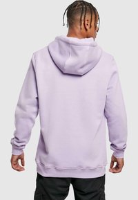 Lila Kapuzenpullover aus weichem Material, mit einer Kängurutasche, gerippten Manschetten und einer Kordelzugkapuze. Glatte Textur und lockere Passform.