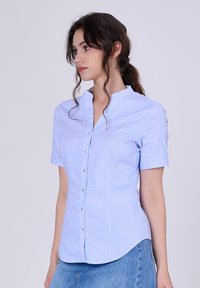 Chemise bleu clair à col avec manches courtes, fermeture à boutons sur le devant, rayures verticales subtiles, coupe ajustée et ourlet arrondi.