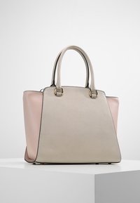 Gestructureerde tote bag met een zachte beige leren buitenkant met een roze accent, twee stevige handvatten en zwarte rand langs de randen.