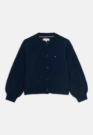 Mornarsko plavi pleteni kardigan s kopčama, dugim naboranim rukavima i malim vezanim logom na lijevoj strani prsa.