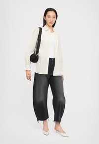 White and beige striped button-up shirt, black denim wide-leg jeans with frayed hem, black circular handbag, and off-white pointed shoes.