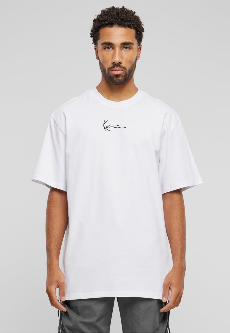 T-shirt en coton blanc à manches courtes, avec un logo noir en signature sur la poitrine. Coupe décontractée et design simple.