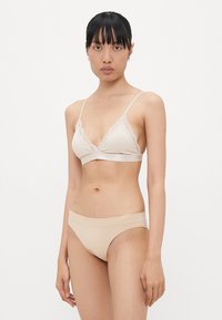 Lichtbeige lingerie set met een delicate bralette met kantafwerking, verstelbare bandjes en een gladde lage bikini slip.