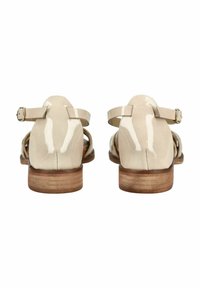 Beige Lackledersandalen mit niedrigem Holzabsatz, ausgestattet mit einem Fersenriemen und einem verstellbaren Schnallenverschluss. Offene Zehenpartie mit minimaler Gestaltung.