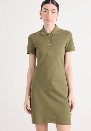 Robe polo vert olive en tissu doux, dotée d'un col, d'une patte de boutonnage et d'un petit logo sur la poitrine gauche.