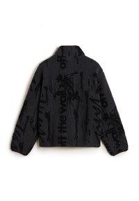 Schwarze Felljacke mit einer gemütlichen Textur, hohem Kragen und auffälligem schwarzen Textmuster auf dem gesamten Stoff. Kurz geschnittenes Design mit langen Ärmeln.