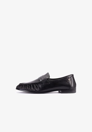 Mocasín de cuero negro con un tacón bajo, diseño delantero plisado y un pequeño logo dorado en el lateral, mostrado desde el lado exterior.