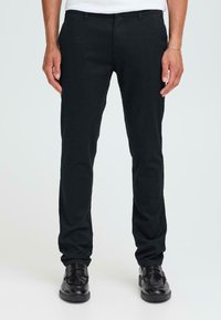Zwarte, slim-fit broek van een katoenen mix. Kenmerken zijn een vlakke voorkant, riemlussen en standaard zakken. Gedragen met zwarte leren schoenen.