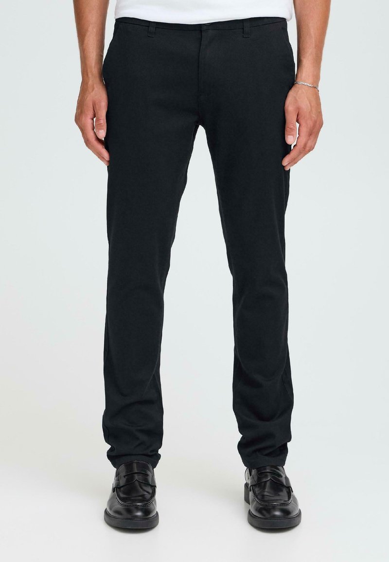 Zwarte, slim-fit broek van een katoenen mix. Kenmerken zijn een vlakke voorkant, riemlussen en standaard zakken. Gedragen met zwarte leren schoenen.