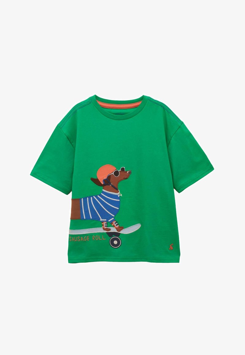 Camiseta verde con un gráfico de un dachshund que lleva gafas de sol, un casco, un suéter a rayas y monta una patineta con la etiqueta "Sausage Roll".